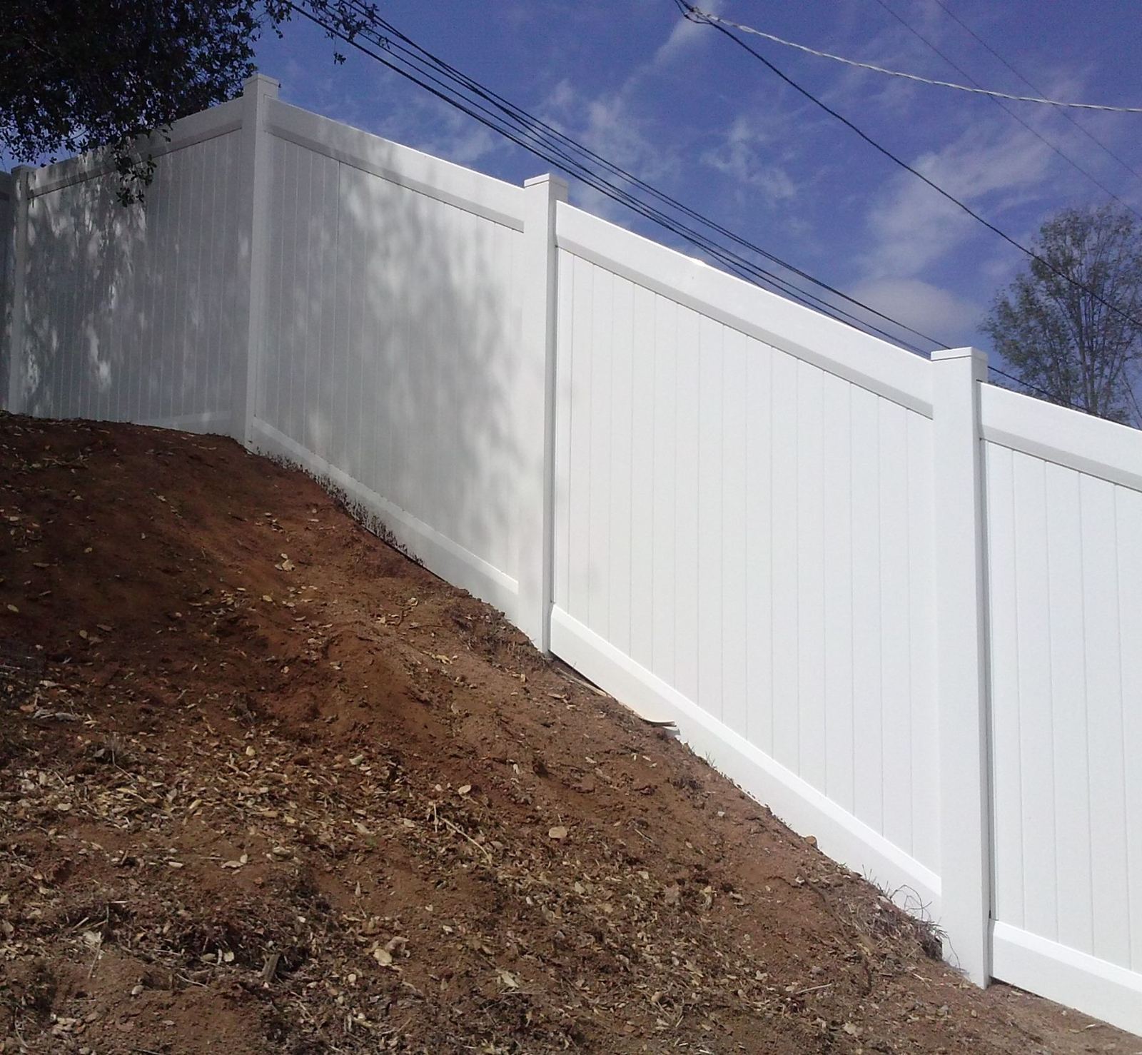 White vinyl privacy fence on a slope