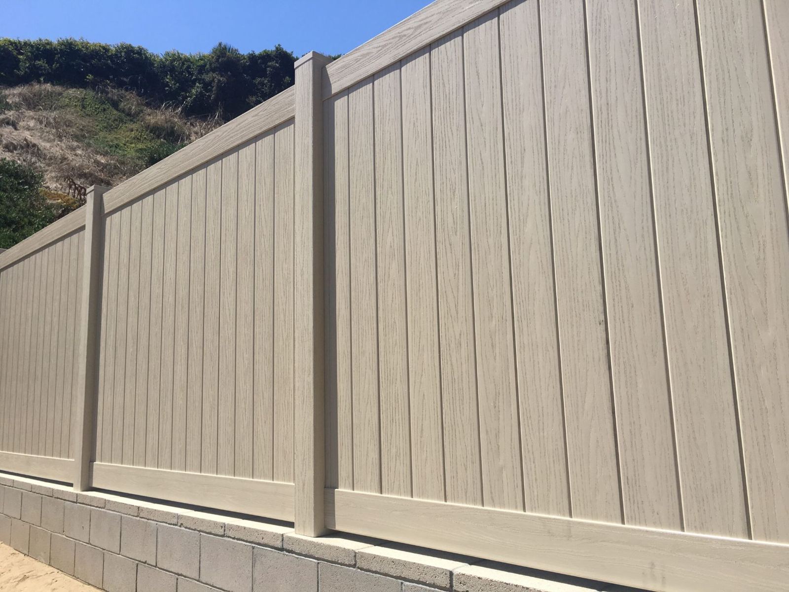 Wood-grain vinyl privacy fence on a block wall